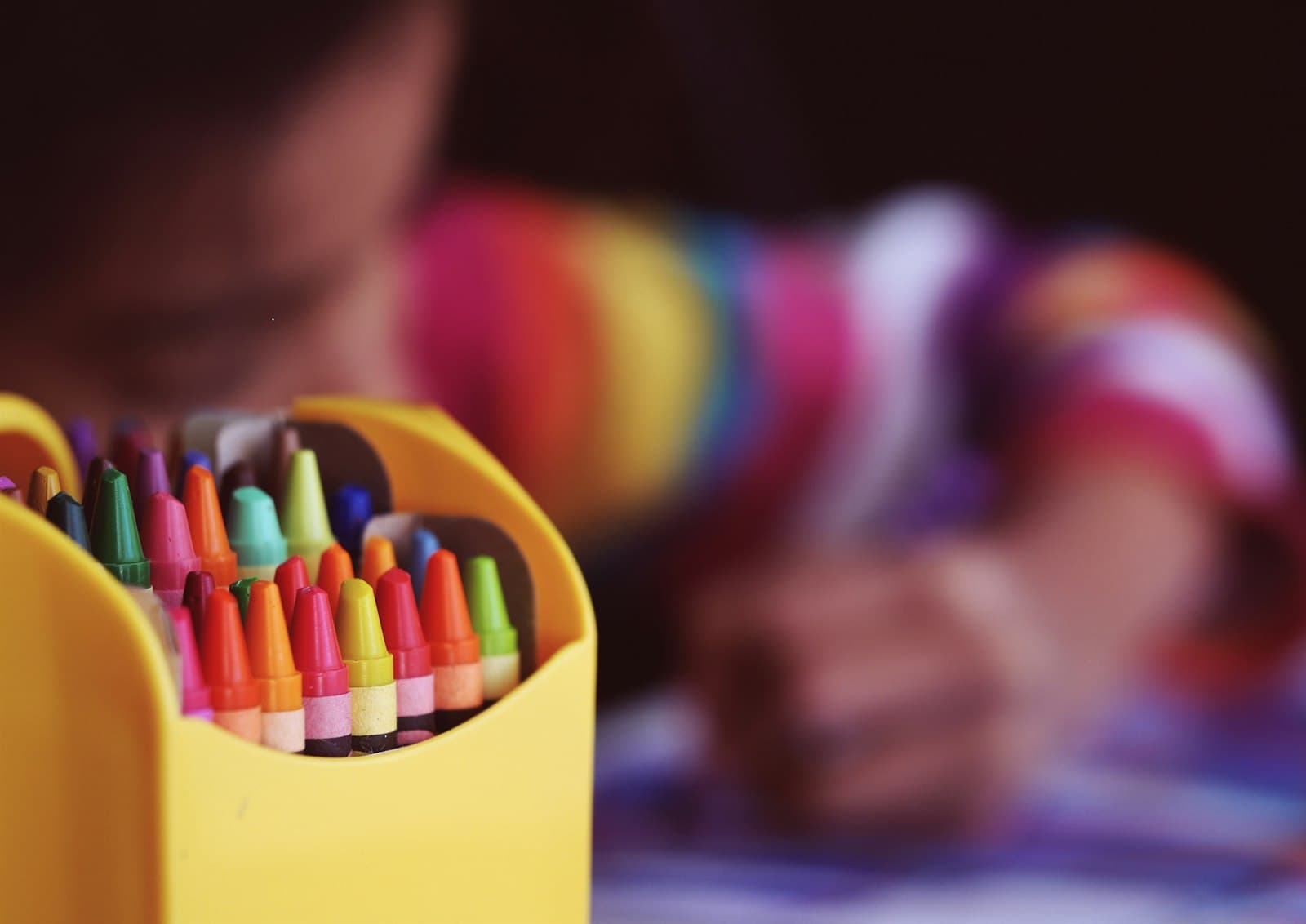 Crayons beside a child coloring