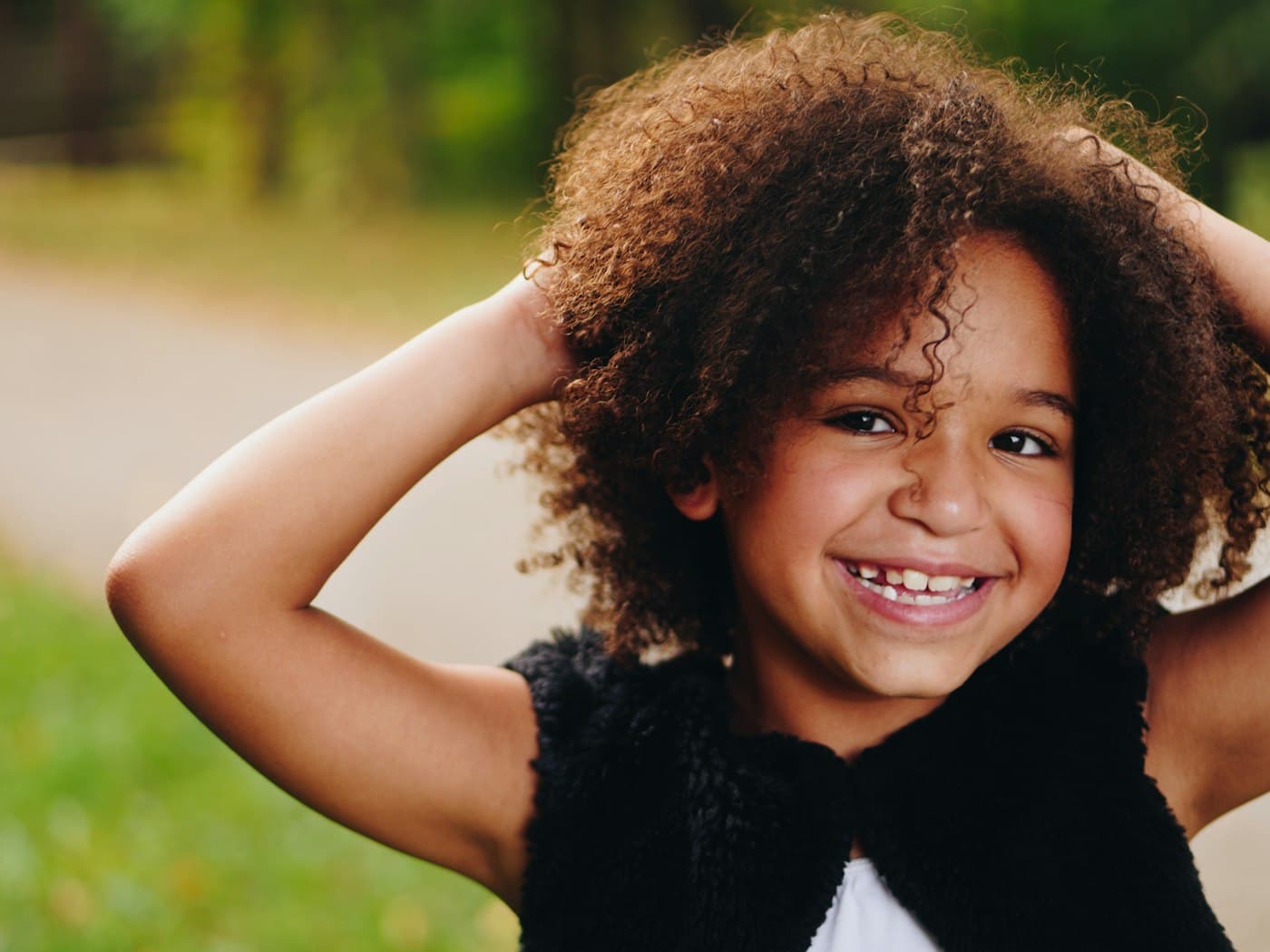 Girl raising both hands in a green field